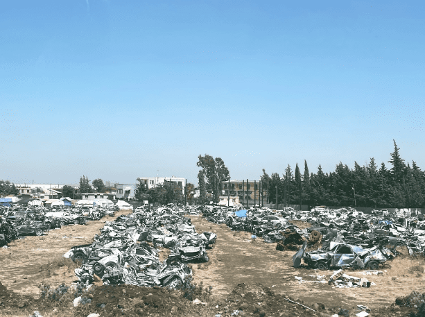 A scene of automobile wreckage lies beneath the ruins of buildings brought down by the earthquake.